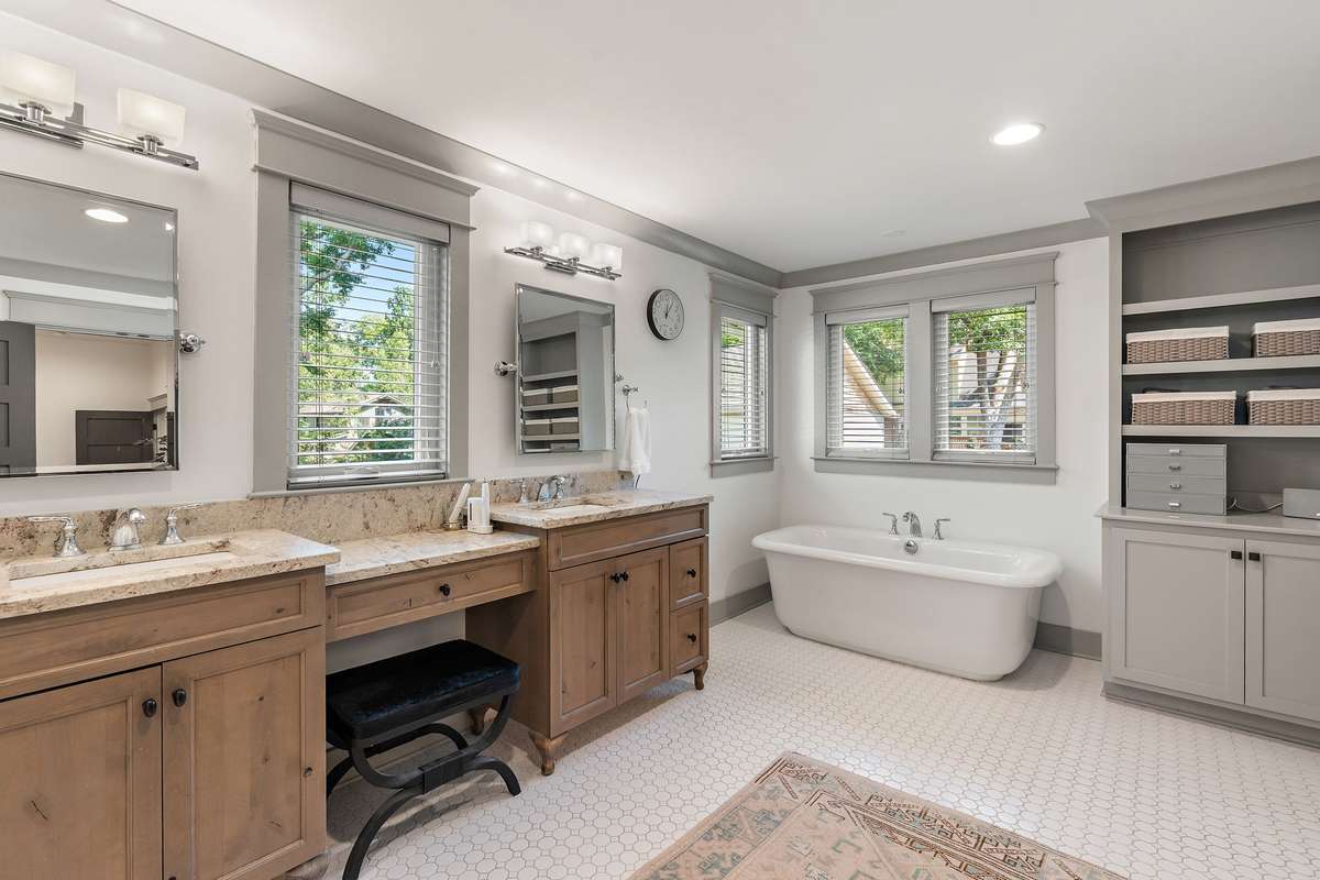 Incredible primary bathroom with storage, separate vanities and the tub is beautifully situated with so much window light.