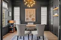 This sophisticated home office with dramatic dark walls, large windows, and abundant natural light greets you upon entry .