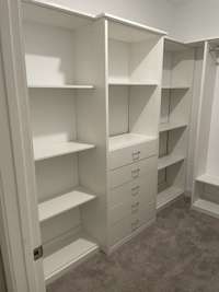 Walk-in closet has custom shelving, drawers, and hanging space for maximum storage