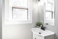 Bright and fresh main level bathroom featuring a classic pedestal sink and updated fixtures.