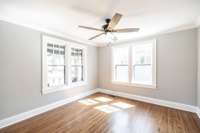 Versatile main level bedroom with hardwood floors and abundant natural light, perfect for a cozy sitting room, home office, or library