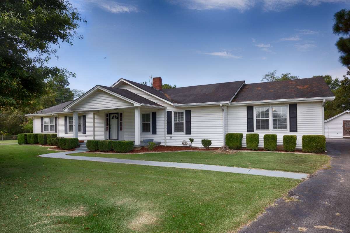 Front of house- Simple landscaping, covered porch, vinyl siding