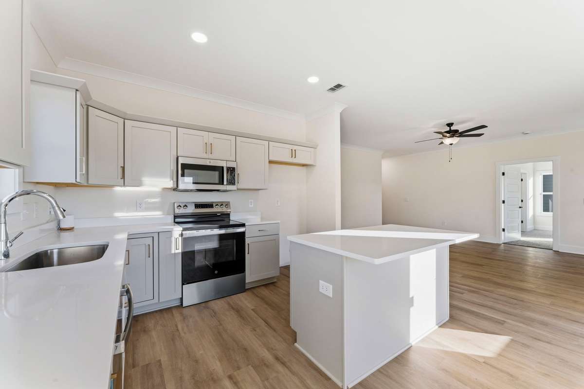 Featuring stainless steel appliances, absolute-white quartz counters, dove-gray cabinets with brass pulls.