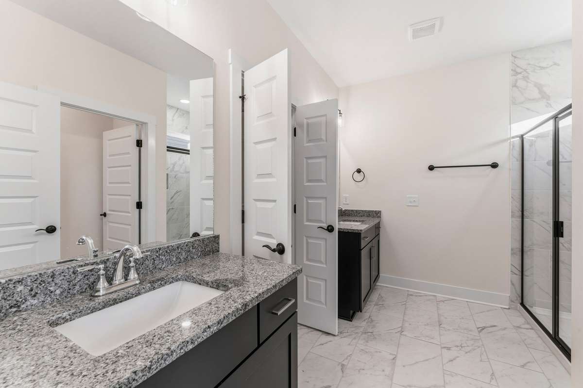 The luxurious primary bathroom is covered in heavily-veined tile including the shower!