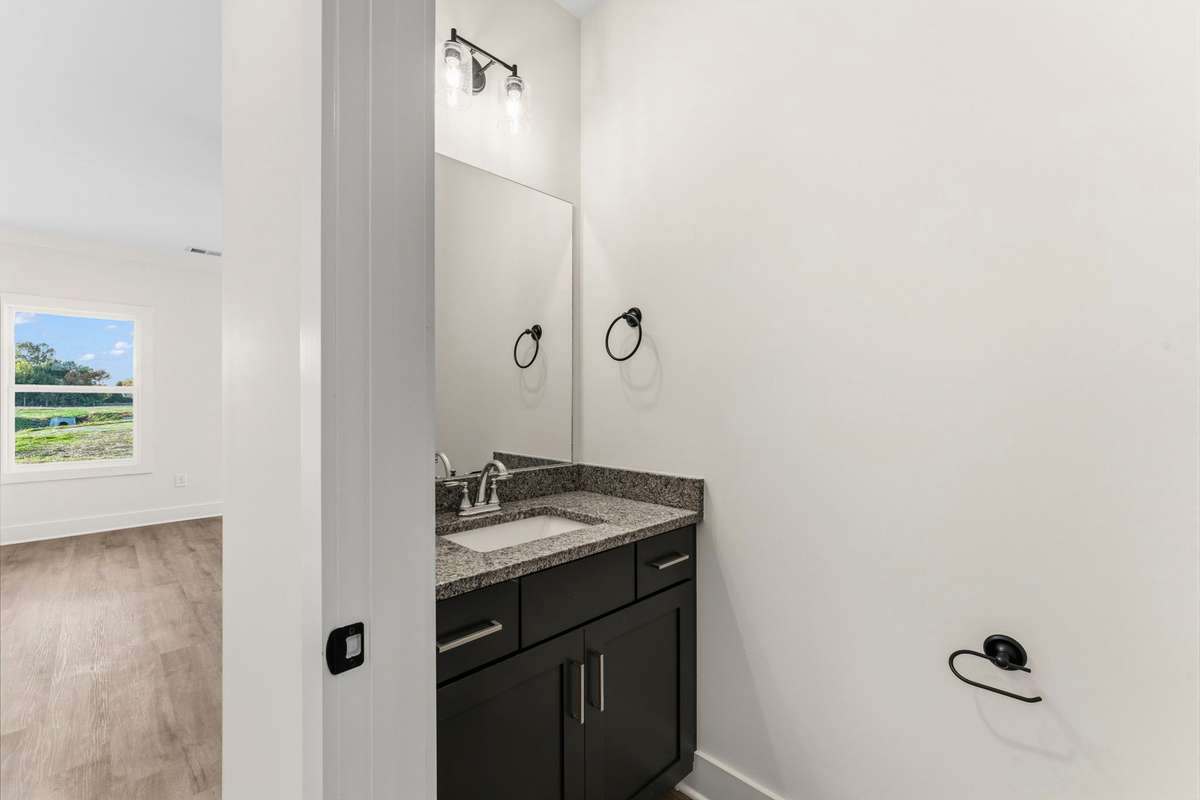 The half bath, located under the stairs has a granite countertop, navy cabinets and brushed nickel pulls.