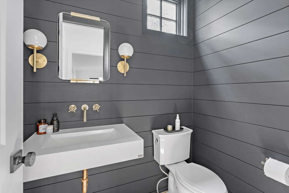 Powder Bath boasts a moody paint color with gorgeous gold plumbing and light fixtures.