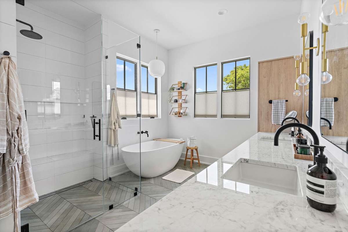 Step into the spa-like Primary Bath with a seamless entry shower, oversized free-standing tub, double vanities + herringbone tile.
