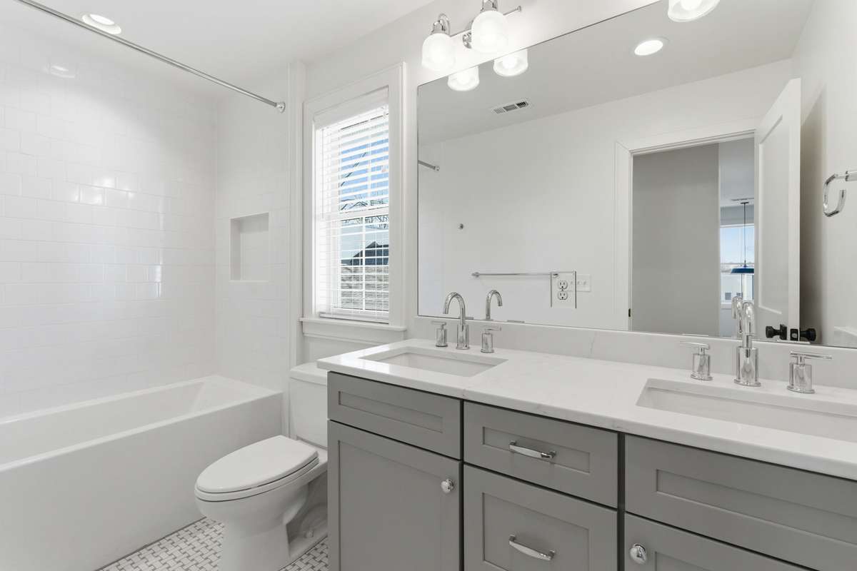 Second and Third Bedrooms share this bathroom with double vanities, shower / tub combo with wall niche + tiled flooring.