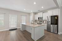 This open kitchen is not only aesthetically pleasing but also functional with the large island, extra cabinet space, plenty of space for barstools, granite counters, top of the line appliances, recessed lighting, and plenty of sunlight