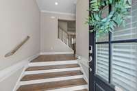 Enter into this foyer to the main level of your new home perfect for adding a coat rack or drop zone bench. Glass front tall door leads into hardwood steps in the foyer as well as hardwood steps to the second level.