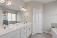 Primary bath suite with double vanities, tile flooring, a private water closet, spa soaking tub, and a walk in spacious tiled shower!