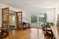 Large living room currently used as an art studio.  You will love the hardwood floors, French doors, and all the natural light from the floor-to-ceiling windows