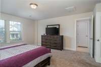 This primary suite is impressively spacious, offering plenty of room for a king-sized bed, additional furniture, and a cozy sitting area.