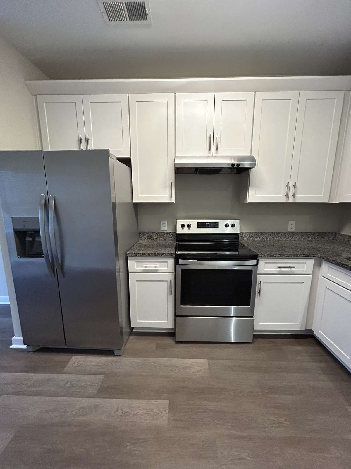 A broader view showcases the generous number of cabinets in this kitchen and the large refrigerator.