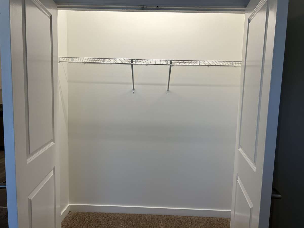 Spacious closet with double doors. Opening the door triggers the lights. It would be easy to add a closet shelving and dividers to hang from the rod.