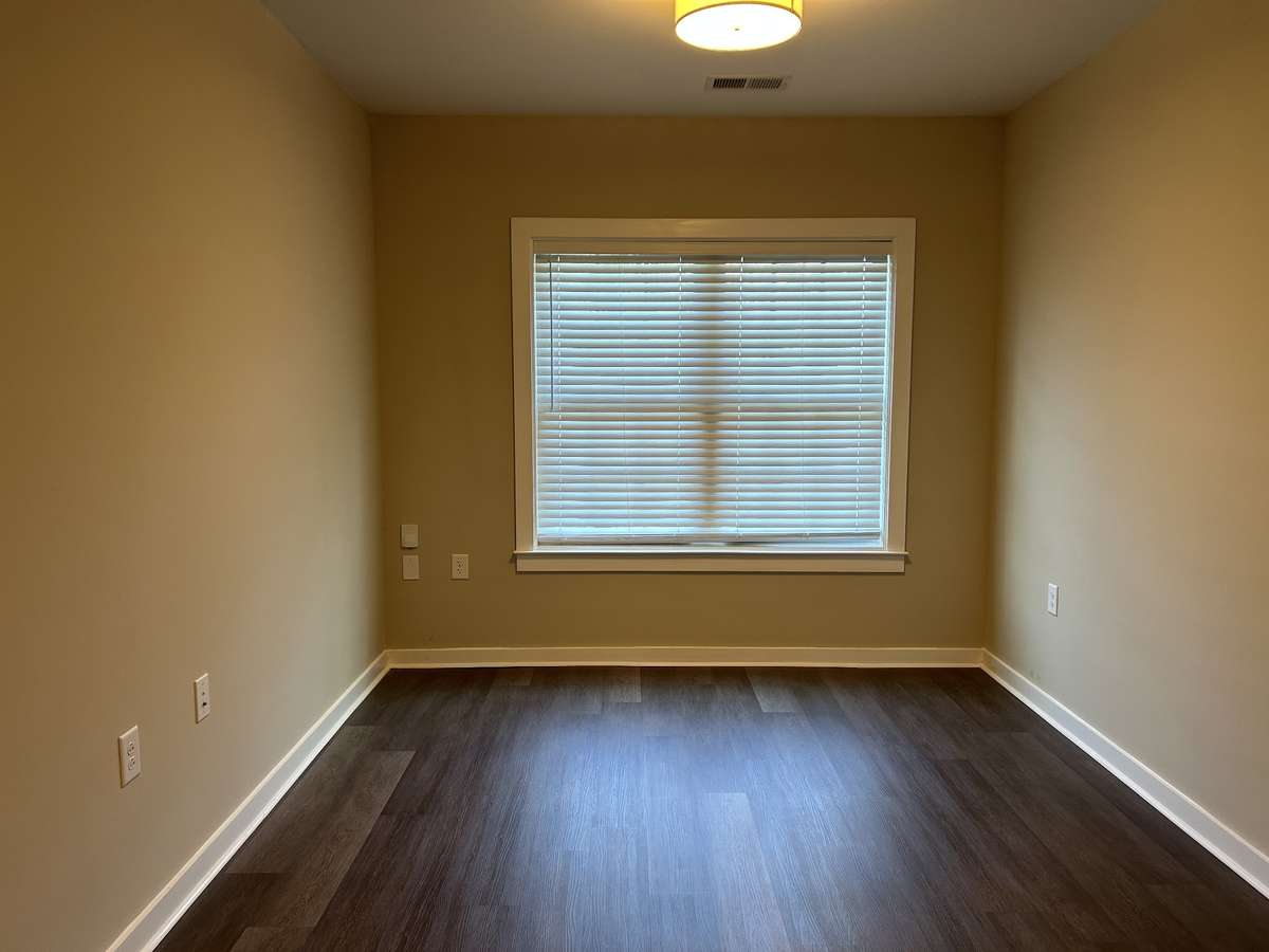From the entry, the living room has a window and easy lift blinds. Space for a sofa, end tables, chairs, and a TV.