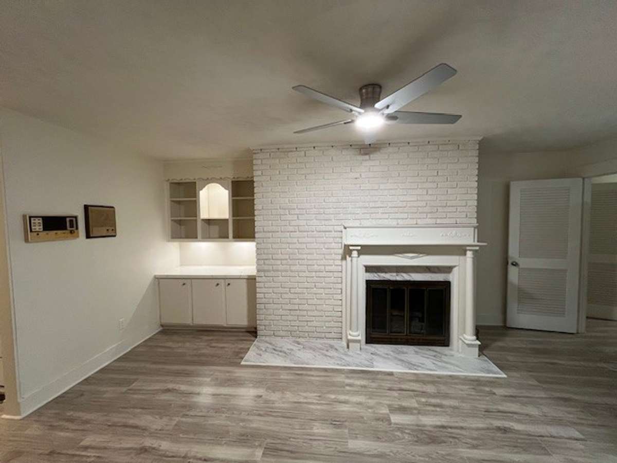 Den with bookshelves and whitewashed fireplace with a detailed antique mantle.