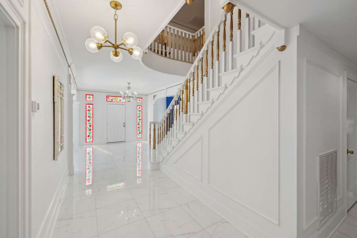 Hallway behind the primary staircase, access to secondary bedroom and pool bath.