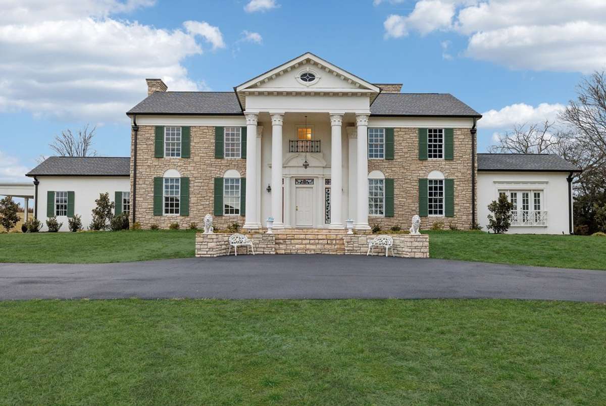The stately stone exterior—accented by signature columns and green shutters—makes a striking first impression.
