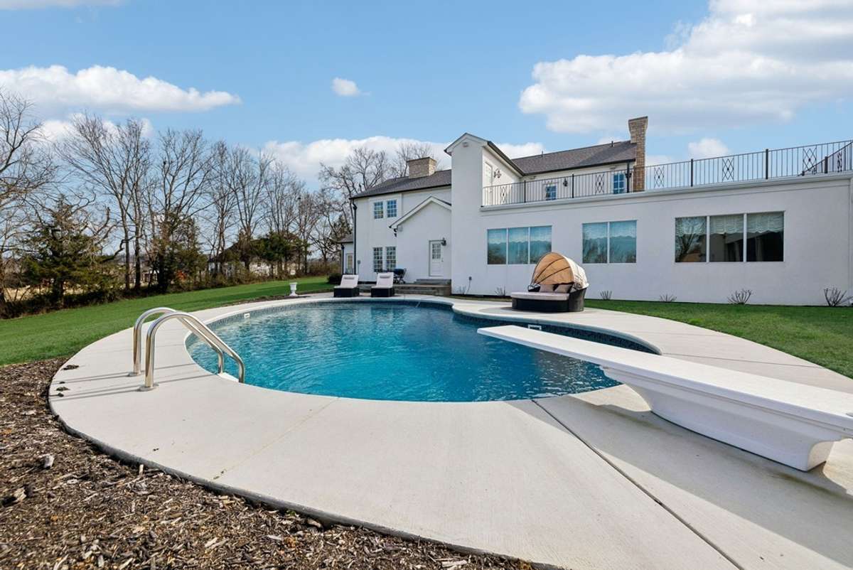 Classic kidney-bean shaped pool with diving board. Second floor terrace overlooking the pool.