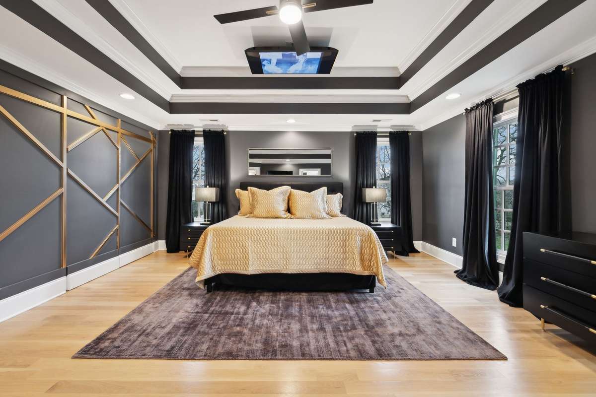Primary bedroom with modern accent wall and TV in the ceiling