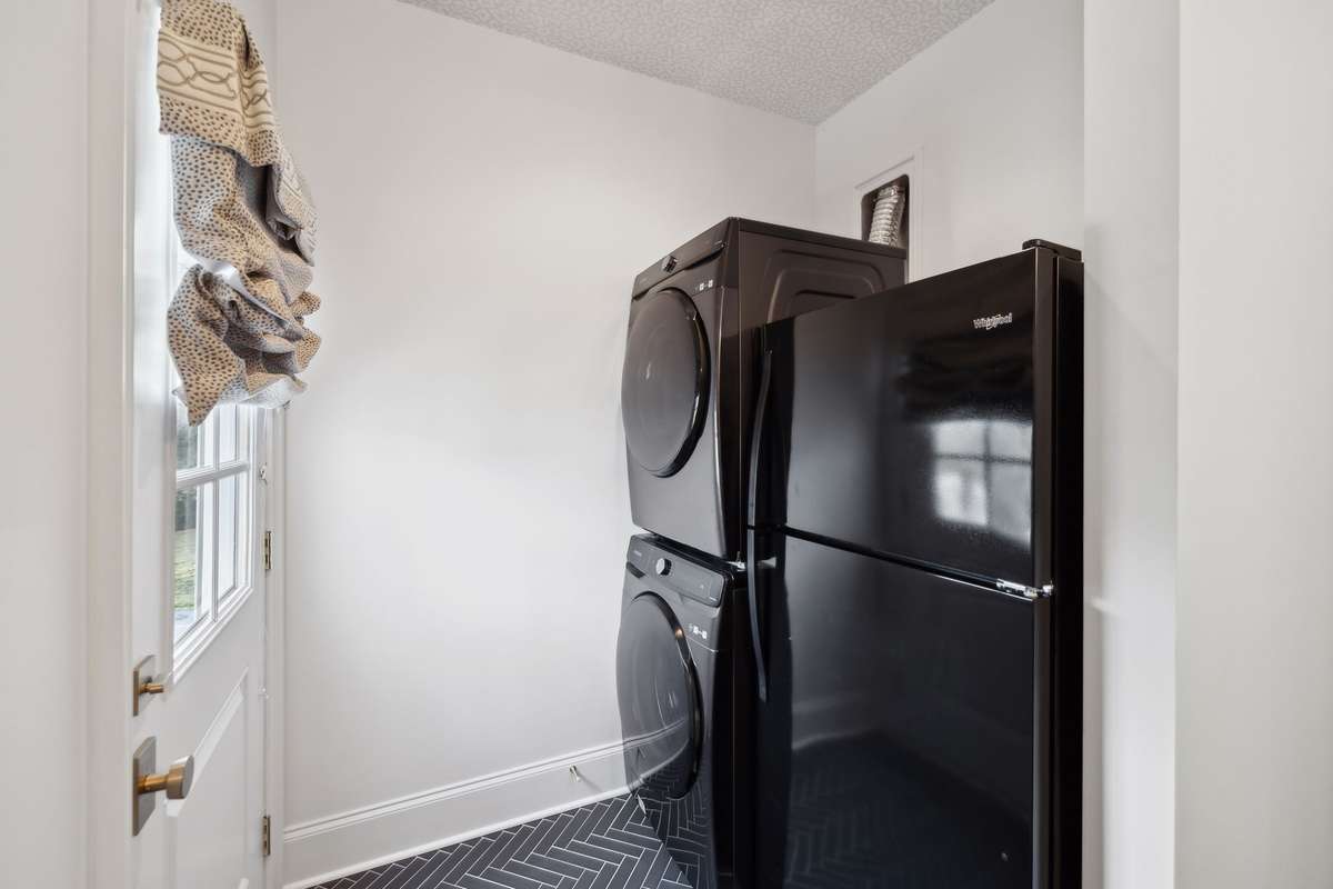 Half bathroom behind primary staircase with access to pool, full laundry, and refrigerator.