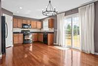 The kitchen boasts a stylish backsplash, sleek granite counters, an updated dining light fixture, and recessed lighting that enhances the warm and inviting space.