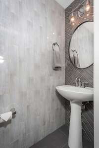 Luxury greets you just off the front door with this upgraded main-level half bath featuring designer tile and modern finishes.
