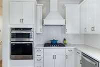 Stylish chef's kitchen with upgraded counters, appliances, backsplash, and soft close cabinetry
