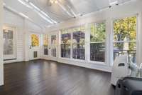 Sunroom offers an enchanting retreat overlooking tree-lined fenced backyard