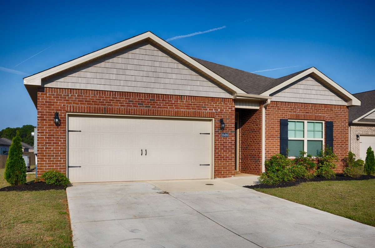 Front of house- Full Brick, concrete drive and walkway, covered front porch, single roll-up door for two-car garage facing road, traditional landscaping