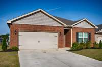 Front of house- Full Brick, concrete drive and walkway, covered front porch, single roll-up door for two-car garage facing road, traditional landscaping