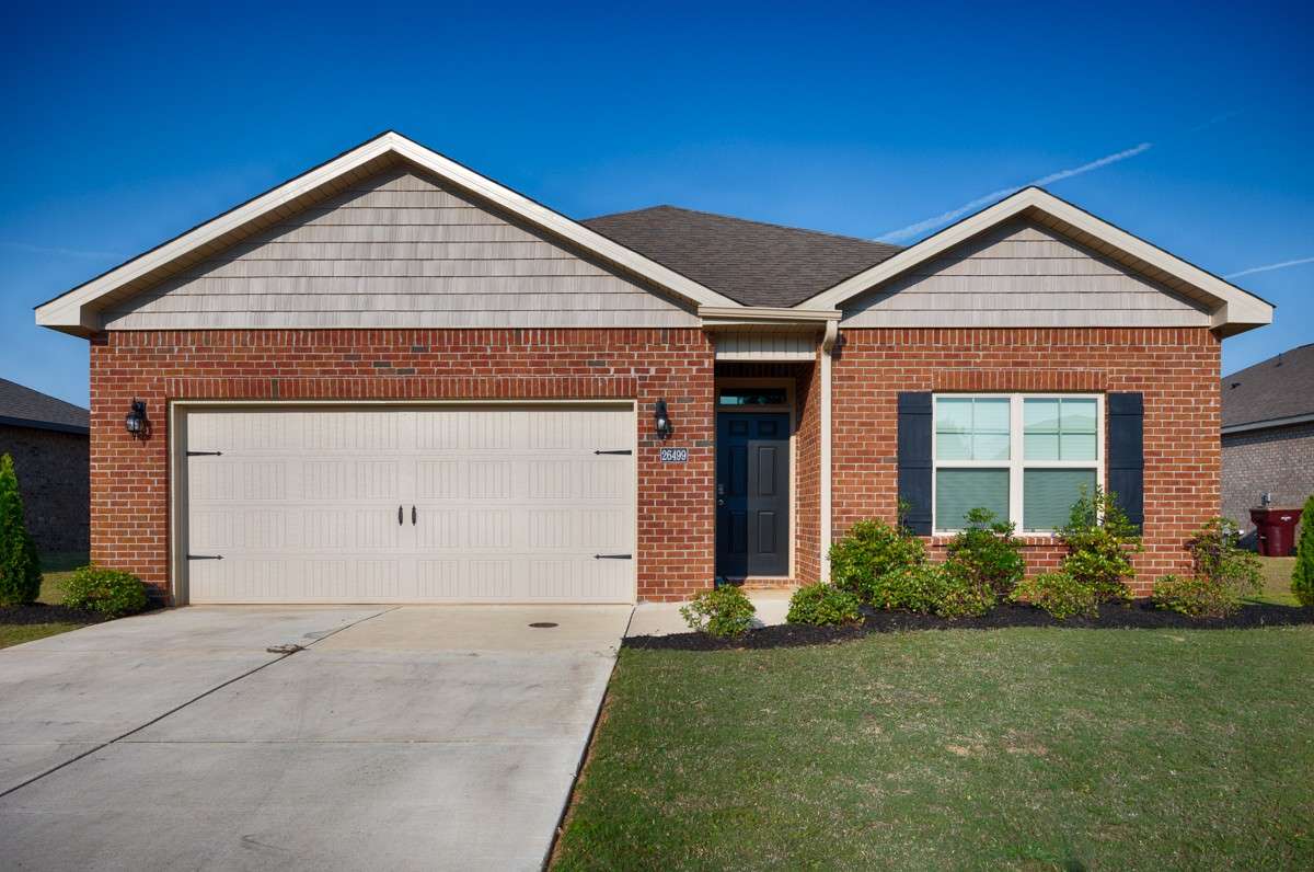 Front of house- Full Brick, concrete drive and walkway, covered front porch, single roll-up door for two-car garage facing road, traditional landscaping