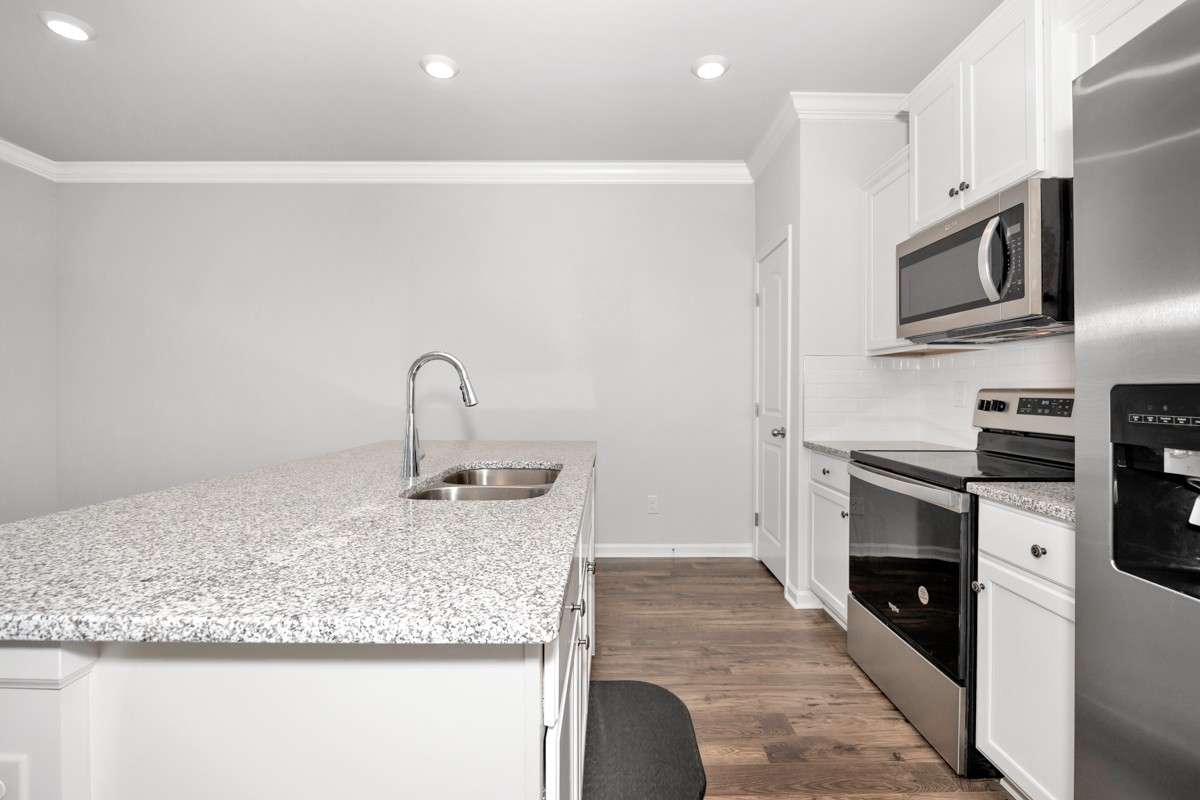Kitchen- lvp flooring, open floorplan, granite countertops, kitchen island with bar seating, pantry, stainless steel appliances- refrigerator, microwave, oven. cooktop