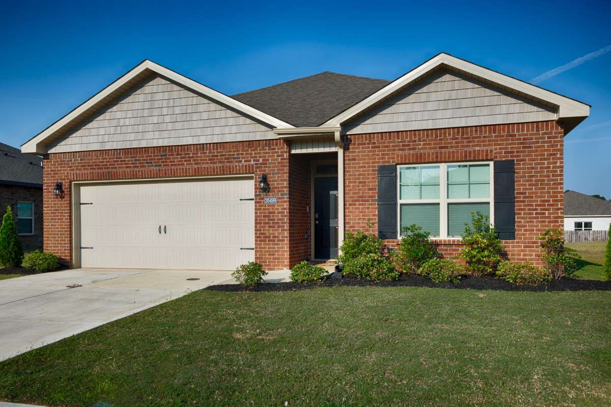 Front of house- Full Brick, concrete drive and walkway, covered front porch, single roll-up door for two-car garage facing road, traditional landscaping