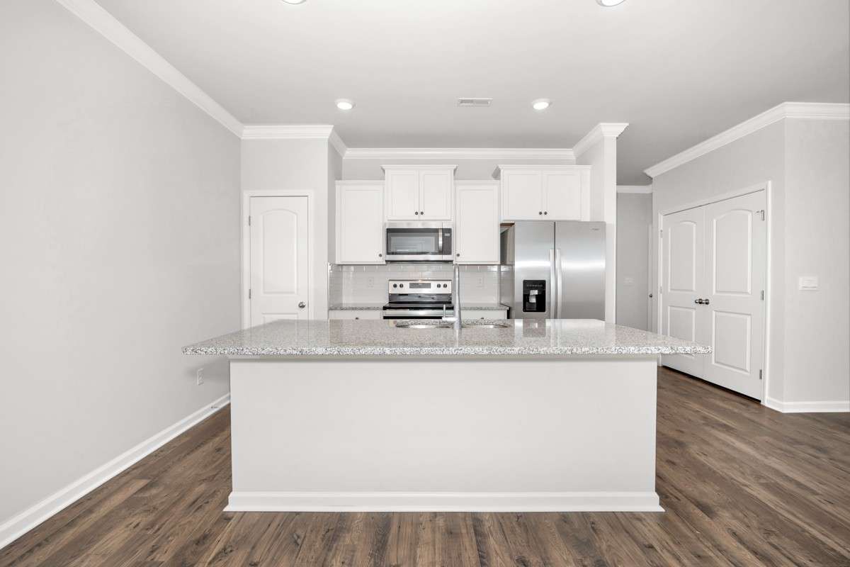 Kitchen- lvp flooring, open floorplan, granite countertops, kitchen island with bar seating, pantry, stainless steel appliances- refrigerator, microwave, oven. cooktop