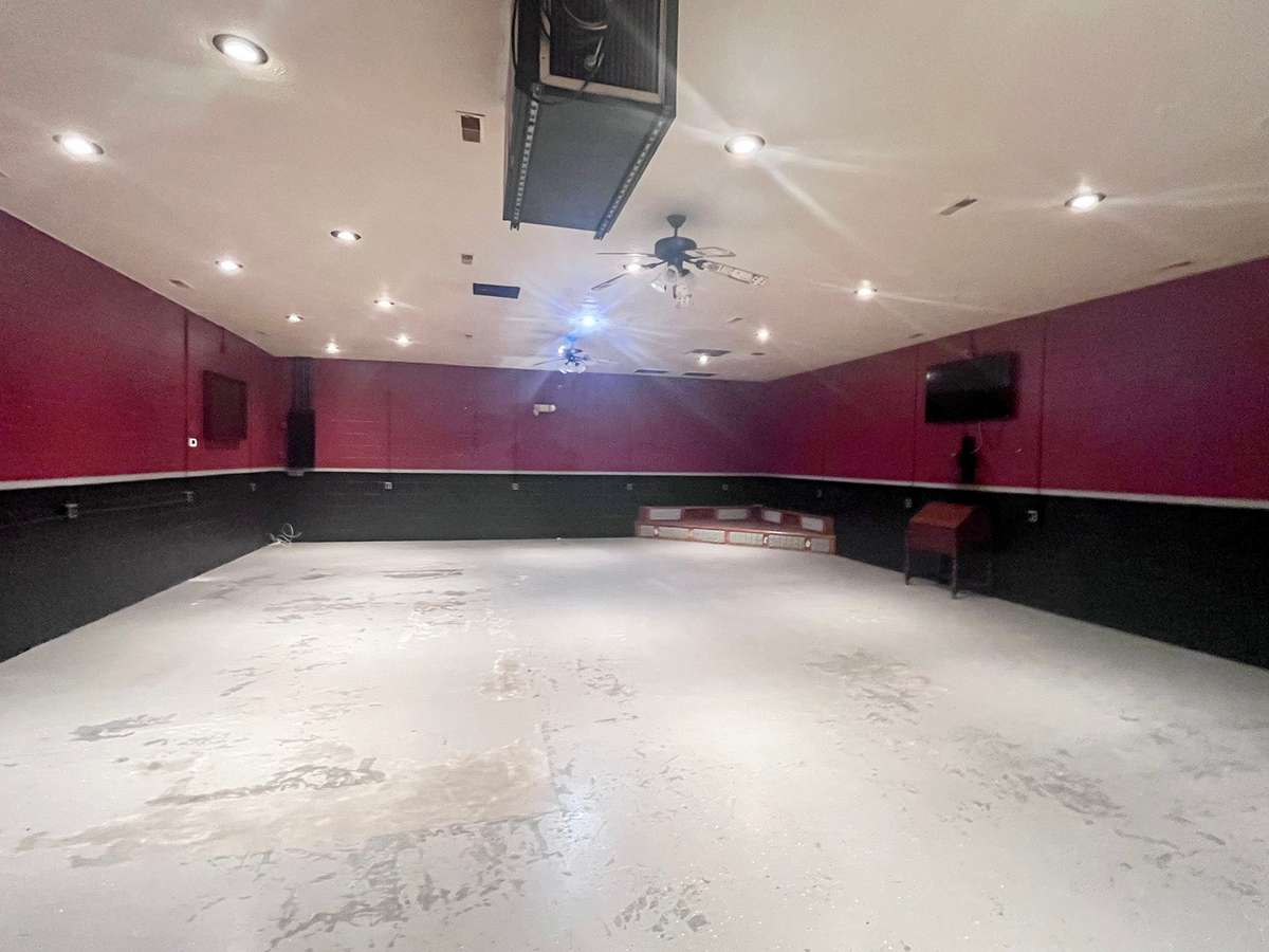 Large open space with stage in corner, and plenty of electrical outlets on wall.