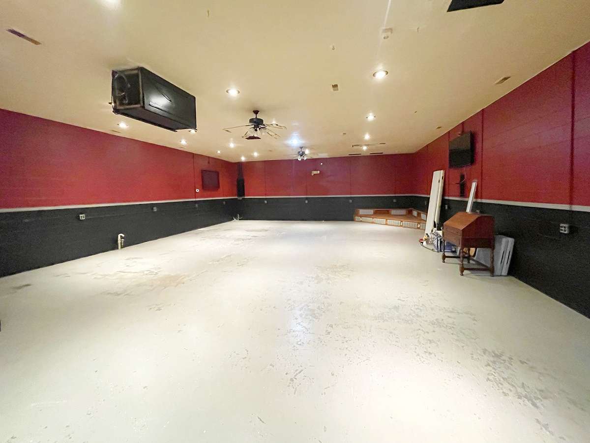 Large open space with stage in corner, and plenty of electrical outlets on wall.