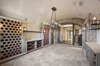 The wine cellar features artistic features including Venetian plaster, terra cotta tile inserts, custom artisan storage built from reclaimed Silver Oak barrels, and 12 magnum racks.