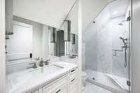 The accompanying bathroom has a single vanity, beautiful tile and marble work, and a walk-in shower.