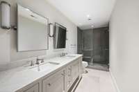 The accompanying bathroom has beautiful tile work and double vanities.