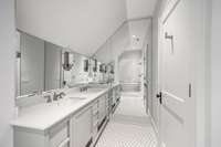 Accompanying this guest room, this is a lavish en-suite bathroom featuring unique tile work, a custom double vanity, and a wet room.