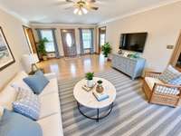 Crown molding with dentil trim detail, raised trey ceiling, wide plank floors and fireplace in elegant living room. Virtually staged photo for inspiration only and to showcase how space can be used and furnished.