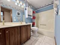 Dual sinks, tile floor, and designer faucets & hardware in guest bathroom.