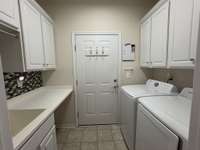 Laundry room with wash sink and cabinets.