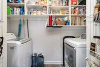 Laundry kept in closet at the end of the kitchen, with lots of custom shelving
