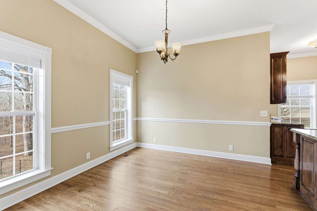 Upscale kitchen showcasing a large granite-topped island with Jenn‑Air cooktop, rich custom cabinetry, built‑in wine storage, and generous counter space, all opening to a cozy breakfast nook perfect for casual dining.