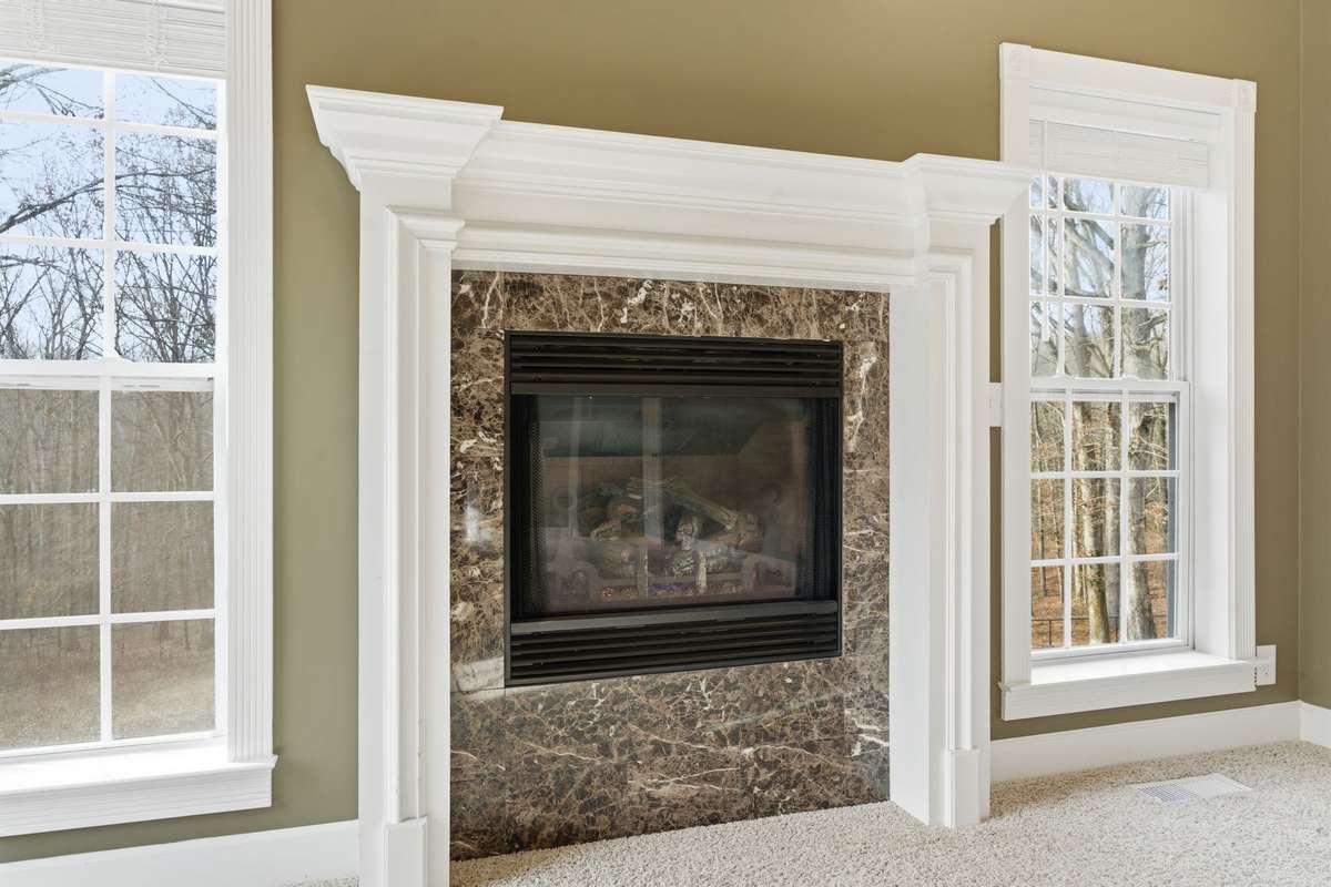 Spacious primary suite with a dramatic double-tray ceiling, cozy fireplace, and wall of windows that fill the room with natural light and peaceful views, creating a serene retreat to begin and end each day.