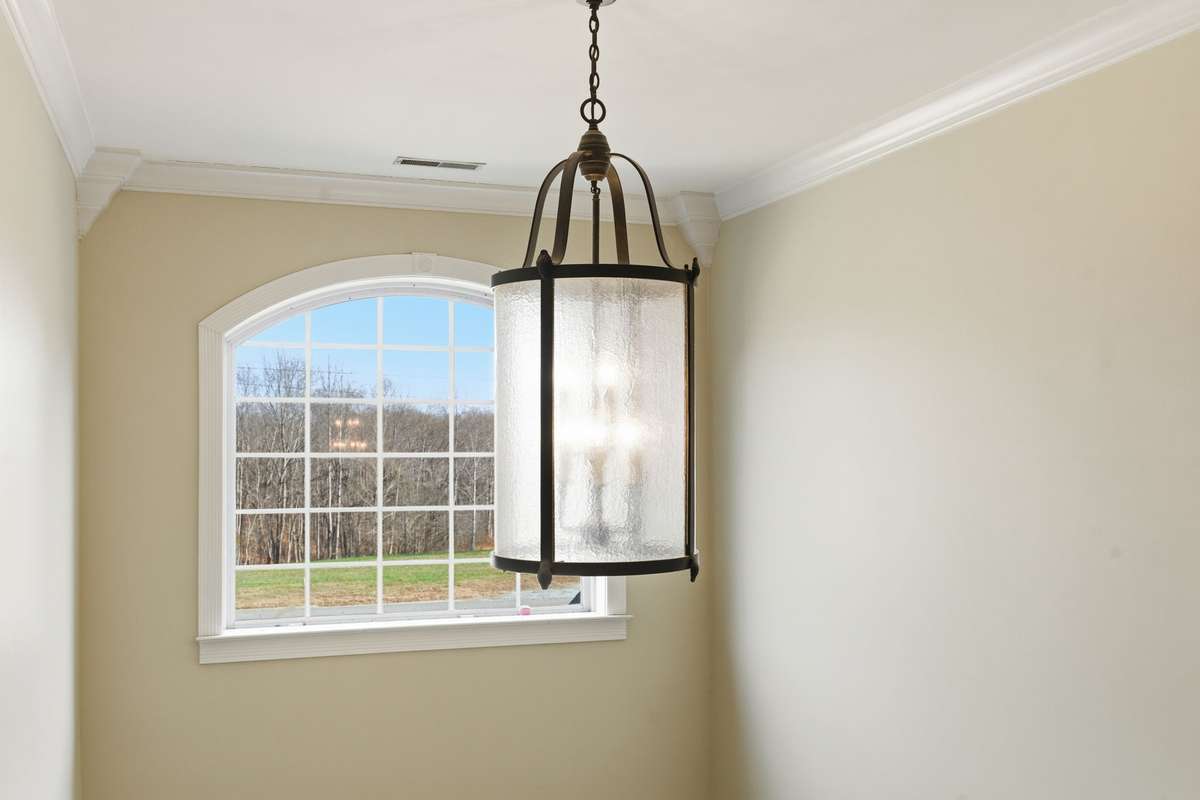 Light-filled upper entry with a large arched window and statement lantern-style fixture, bringing in tons of natural light and highlighting the home’s elegant front foyer.