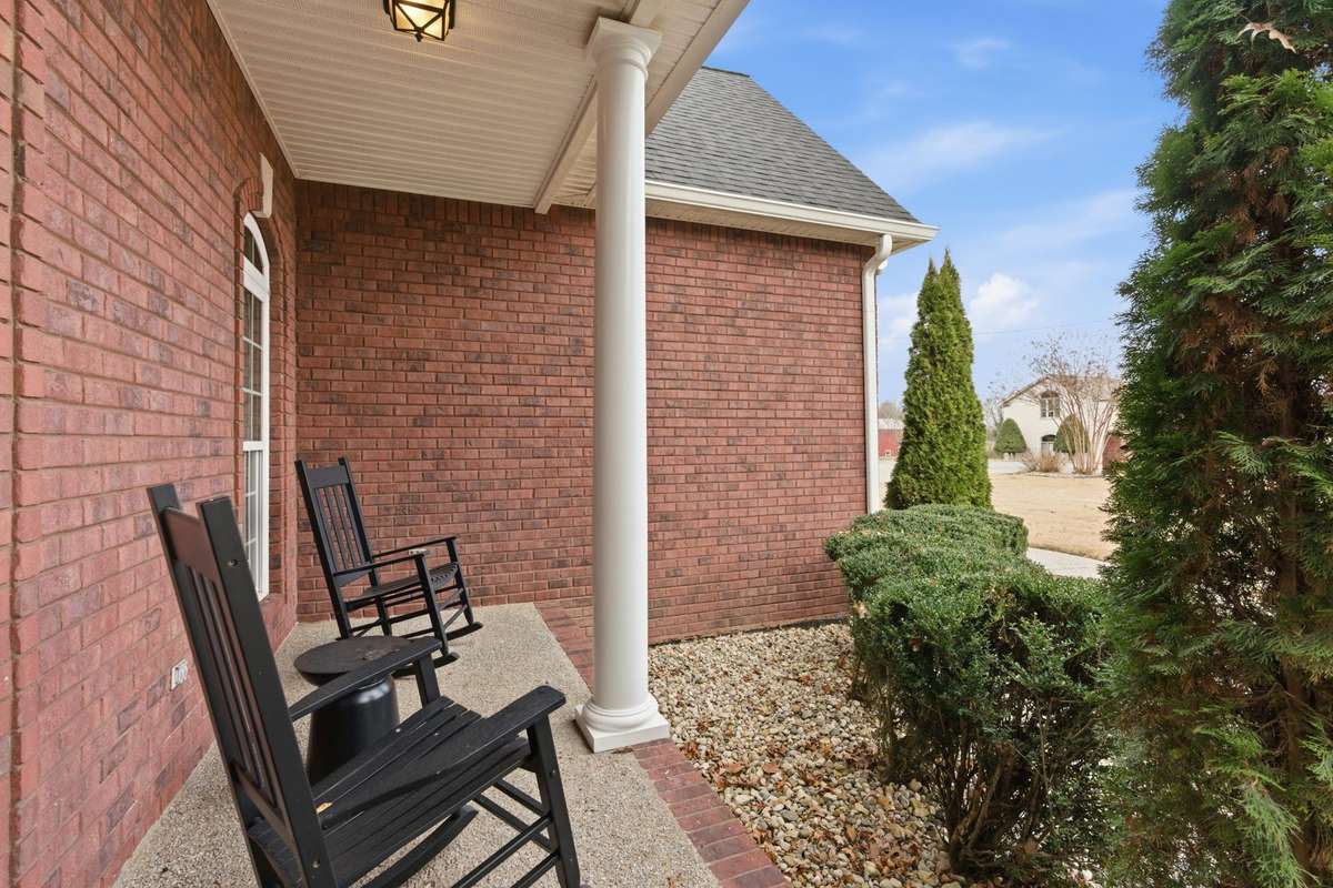 Charming covered front porch with classic columns, decorative glass double doors, and room for rocking chairs, creating a warm Southern welcome the moment you arrive.